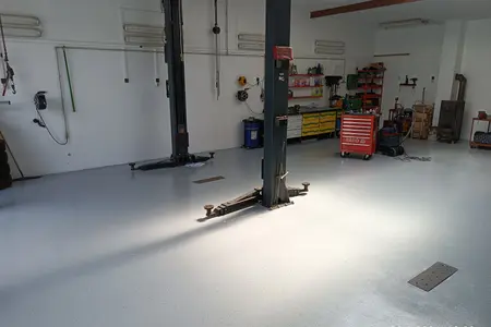 Autoservis. Epoxidová stěrka v barvě RAL 7001 pohozená akrylátovým černobílým chipsem