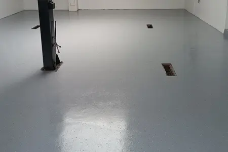 Autoservis. Epoxidová stěrka v barvě RAL 7001 pohozená akrylátovým černobílým  chipsem